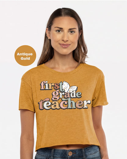 A woman wearing a yellow t-shirt with the text "first grade teacher" printed on it.