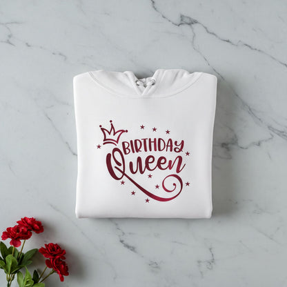 A white hoodie with a red text design that says "BIRTHDAY QUEEN" and stars, along with a crown icon, is displayed on a marble surface.