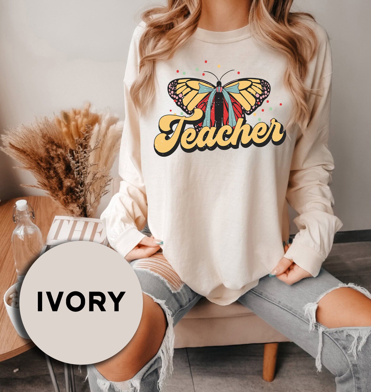 a woman sitting on a couch wearing a sweatshirt with a butterfly on it