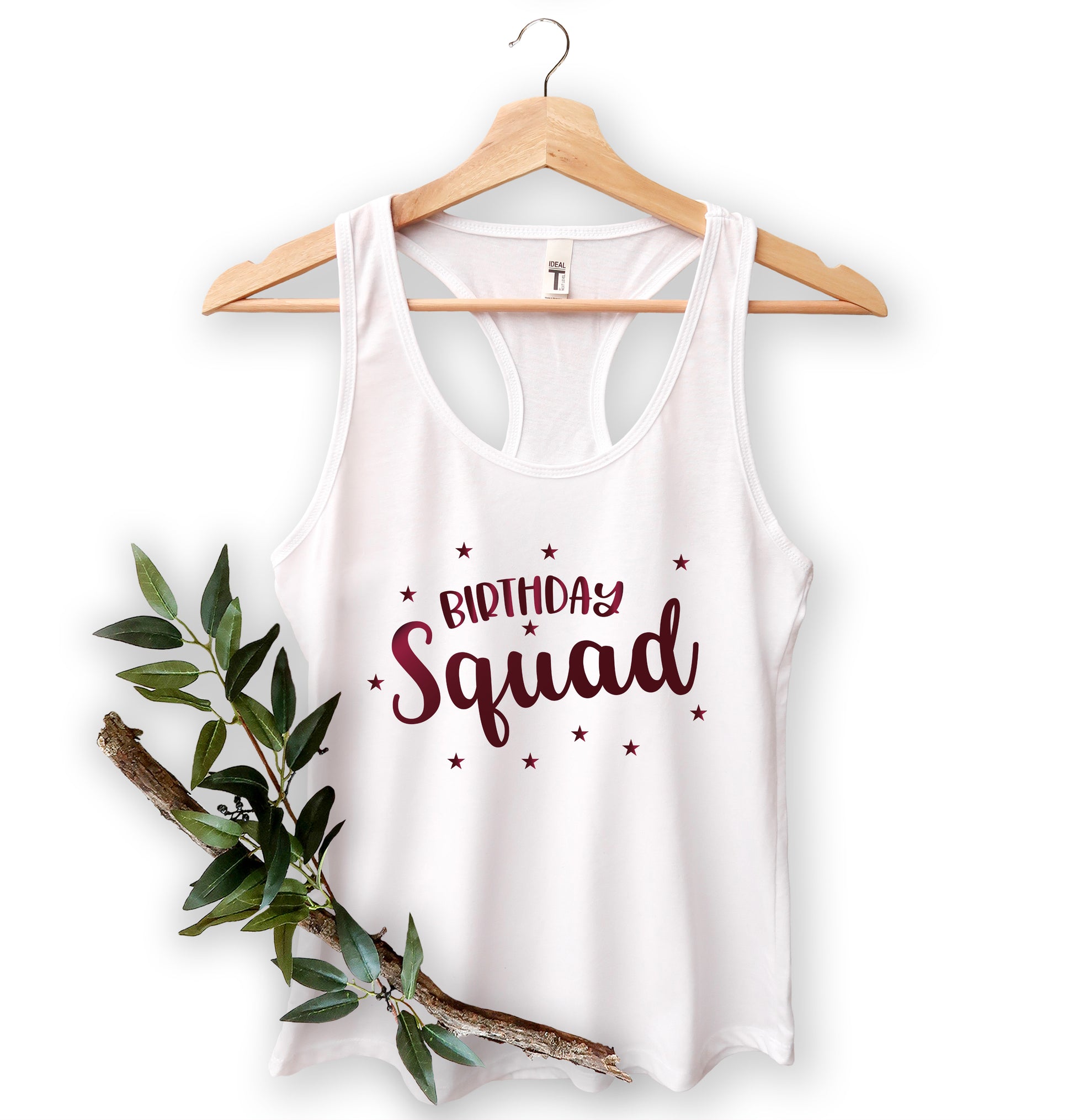 A white tank top with the text "Birthday Squad" printed on it, hanging on a wooden hanger.