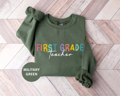 a green sweatshirt with the words first grade teacher printed on it