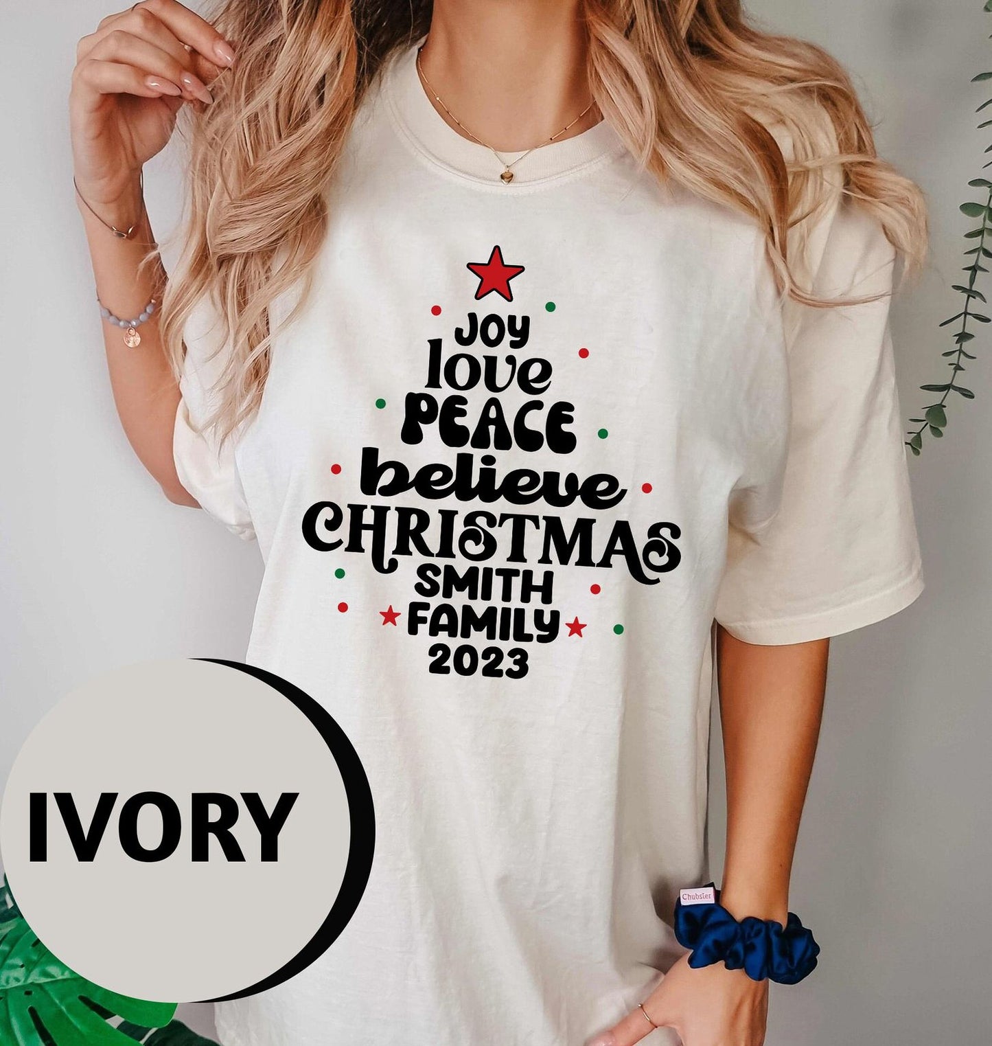 A woman wearing a white t-shirt with a Christmas tree design and text printed on it.