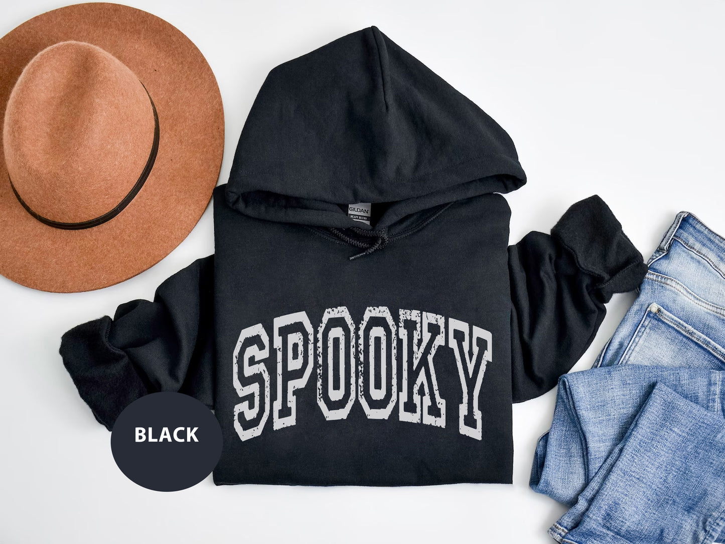 a black hoodie with the word spooky on it next to a hat