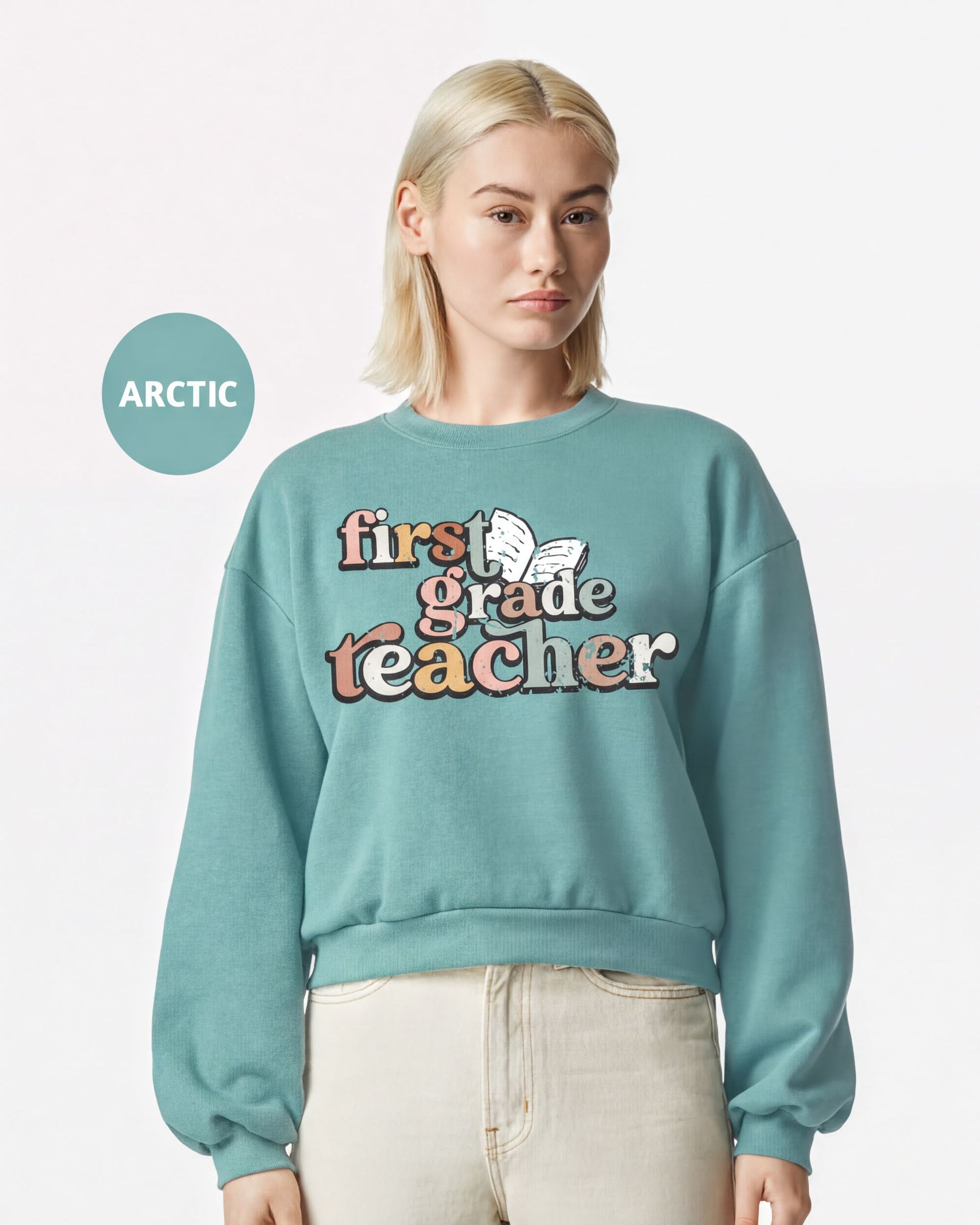 A woman wearing a teal sweatshirt with the text "first grade teacher" printed on it.