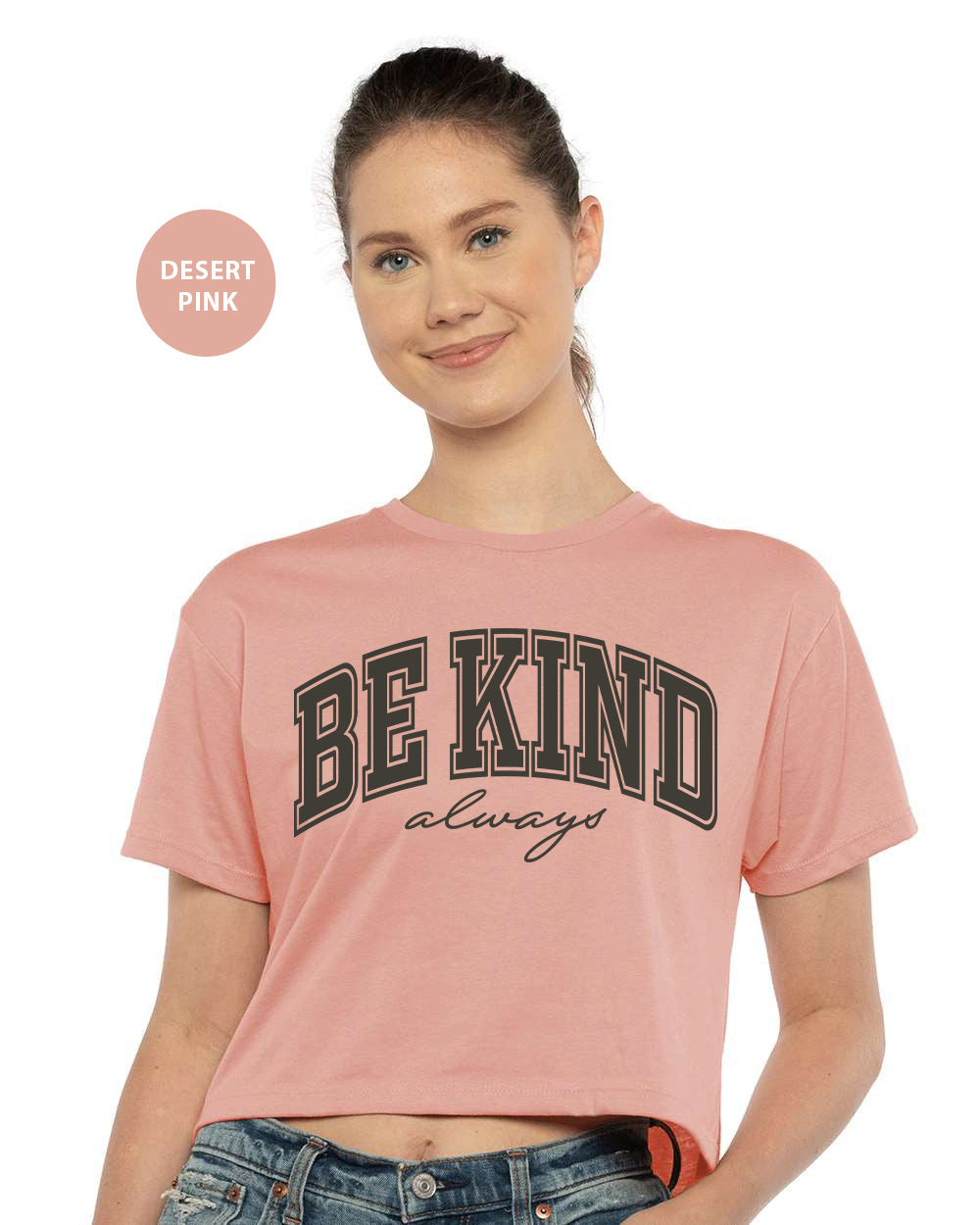 a woman wearing a pink shirt with the words be kind on it