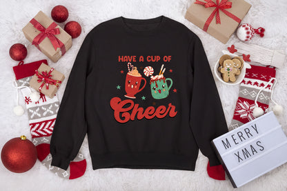 A black sweatshirt with a red and green design, surrounded by Christmas-themed items such as gift boxes, ornaments, and a gingerbread man.
