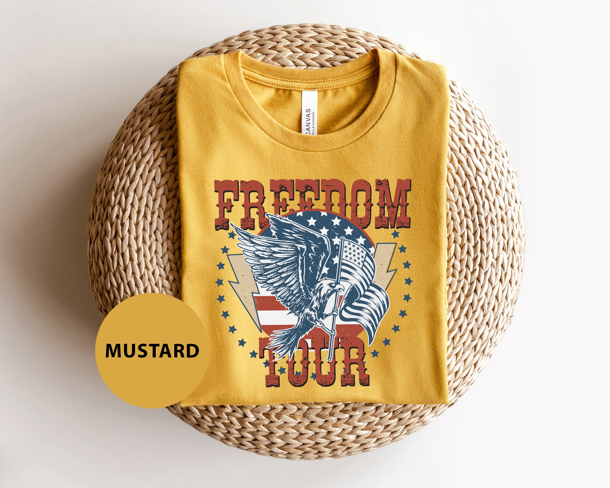 A yellow t-shirt with a graphic design featuring an eagle and the word "FREEDOM" printed on it, along with a circular yellow label that says "MUSTARD".