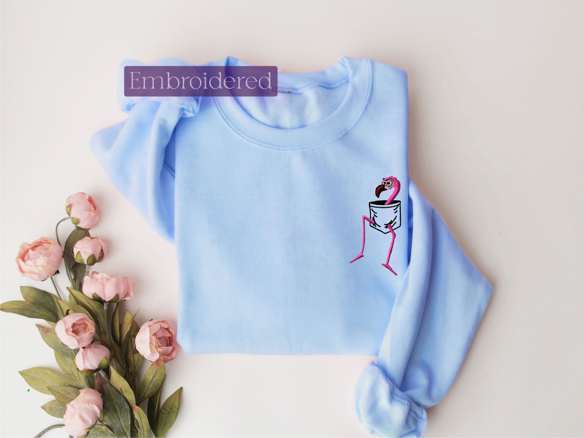 a blue sweater with a pink flamingo embroidered on it