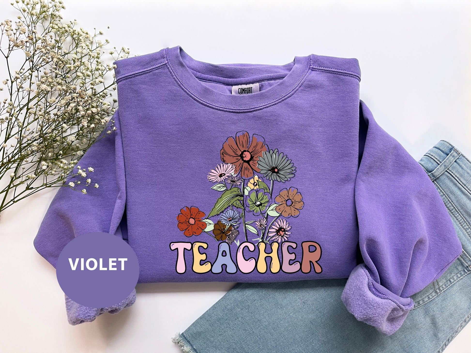 a purple shirt that says teacher with flowers on it