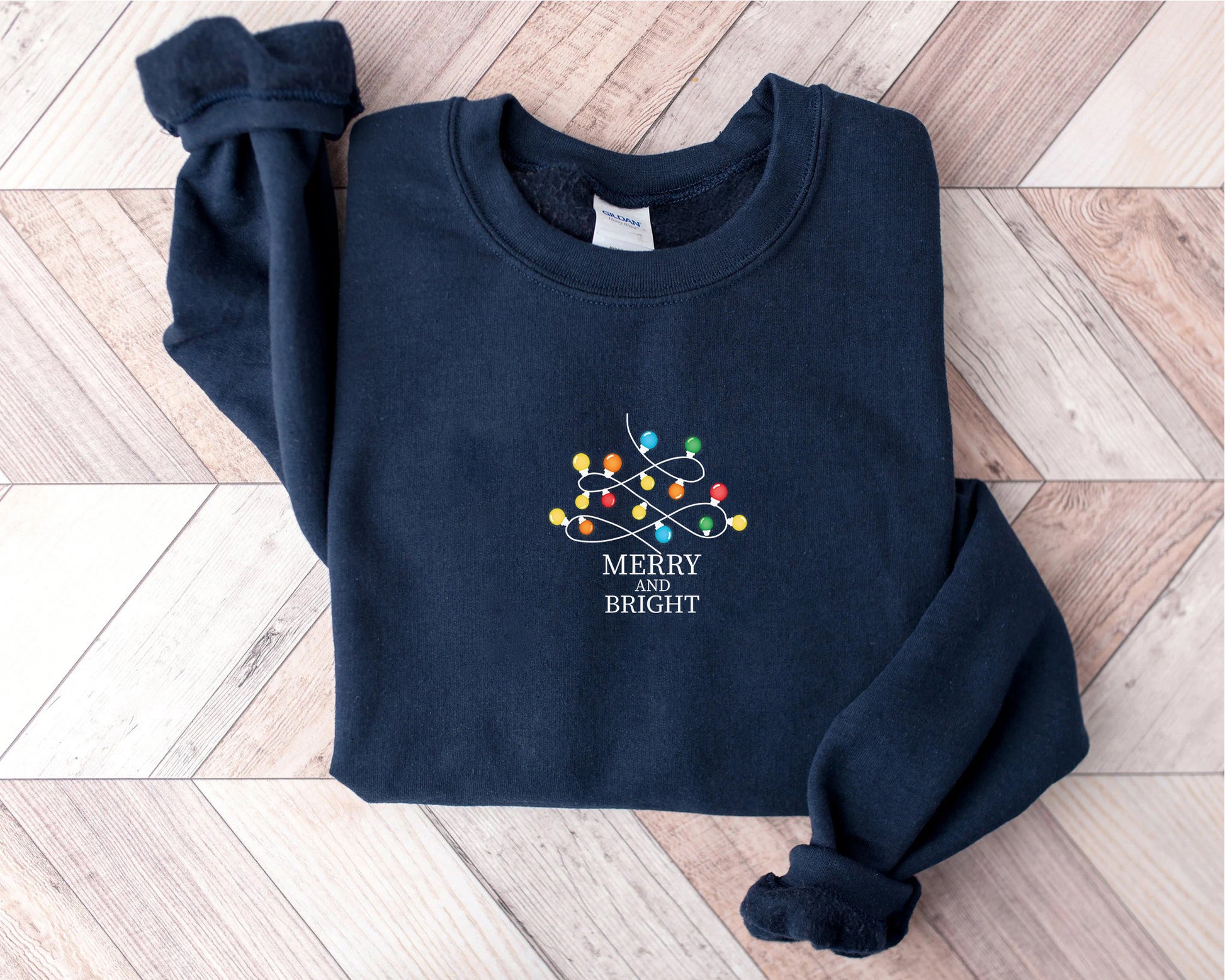 A navy blue sweatshirt with a white Christmas-themed design and the text "MERRY BRIGHT" printed on it.