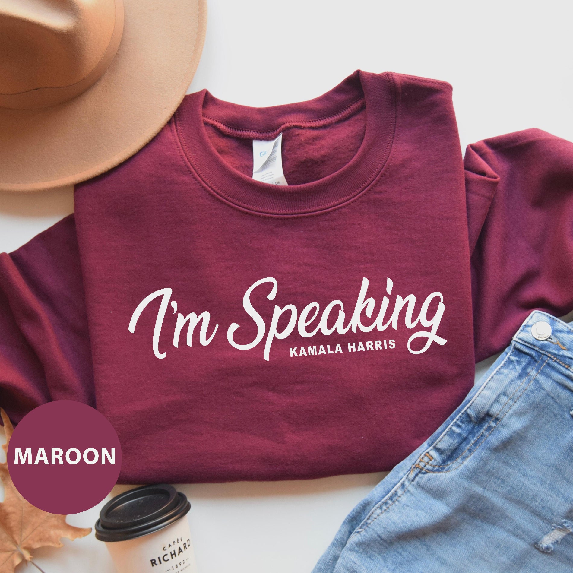 a maroon shirt that says i'm speaking with a hat, jeans, and