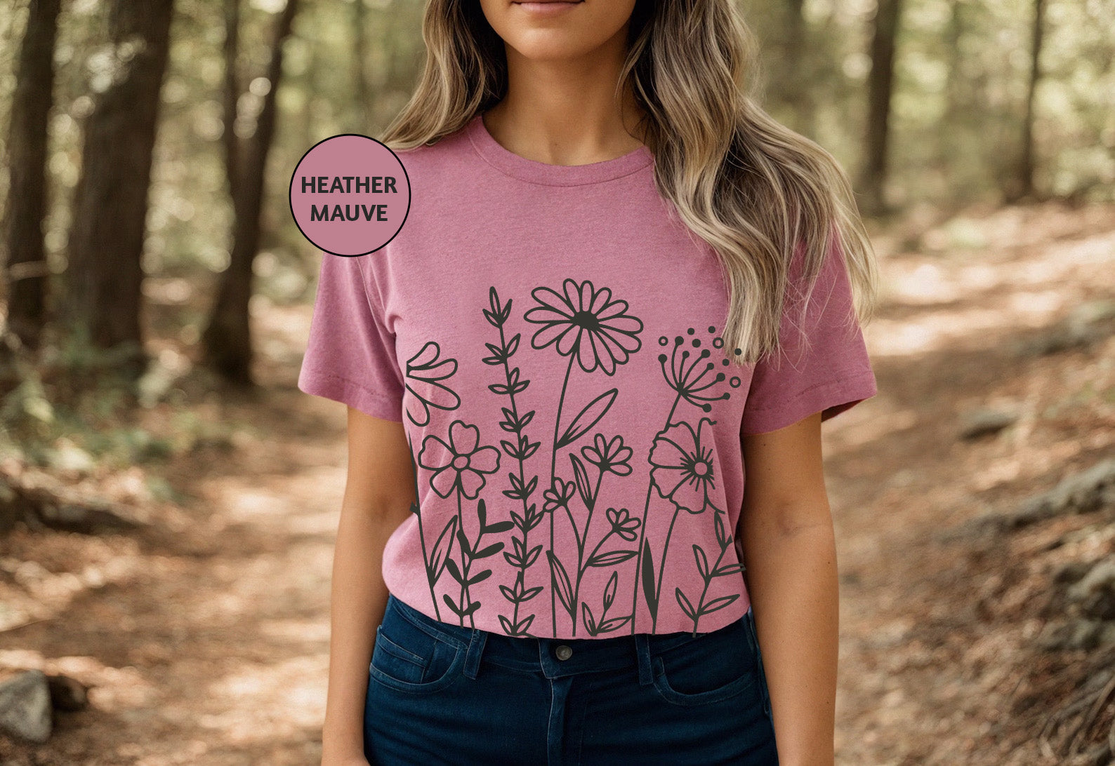 a woman standing in the woods wearing a t - shirt with flowers on it