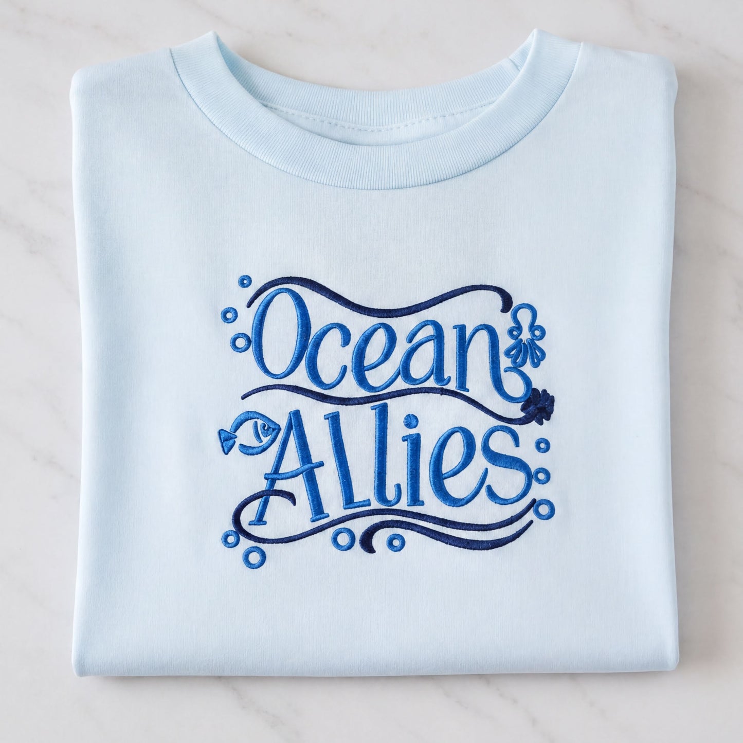 A light blue t-shirt with the text "Ocean Allies" embroidered on it.