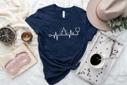 a blue t-shirt with a white line design, a hat, a book, a cup of coffee, and some other items arranged on a bed.