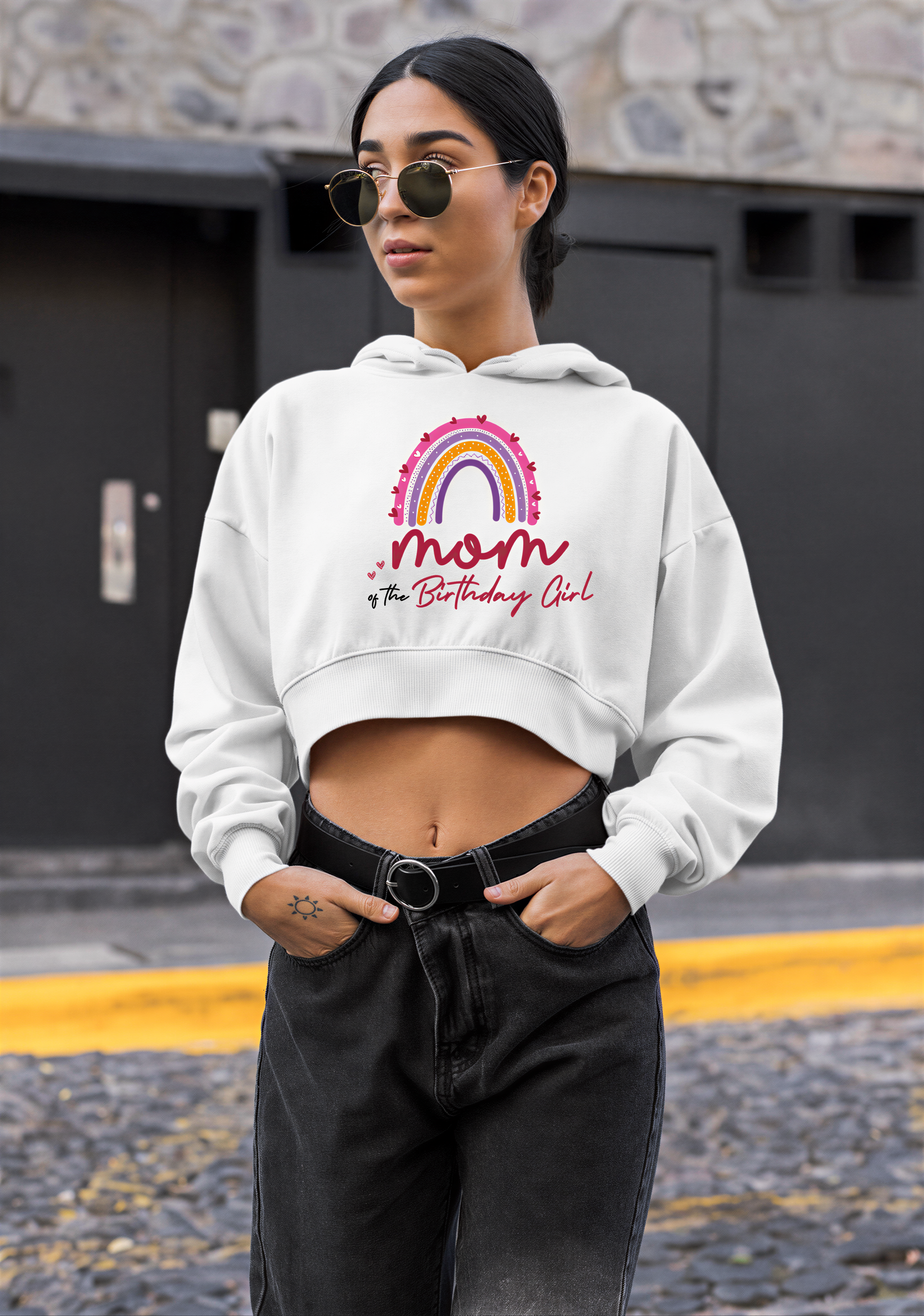 A woman wearing a white hoodie with a graphic design and text, standing in front of a building.