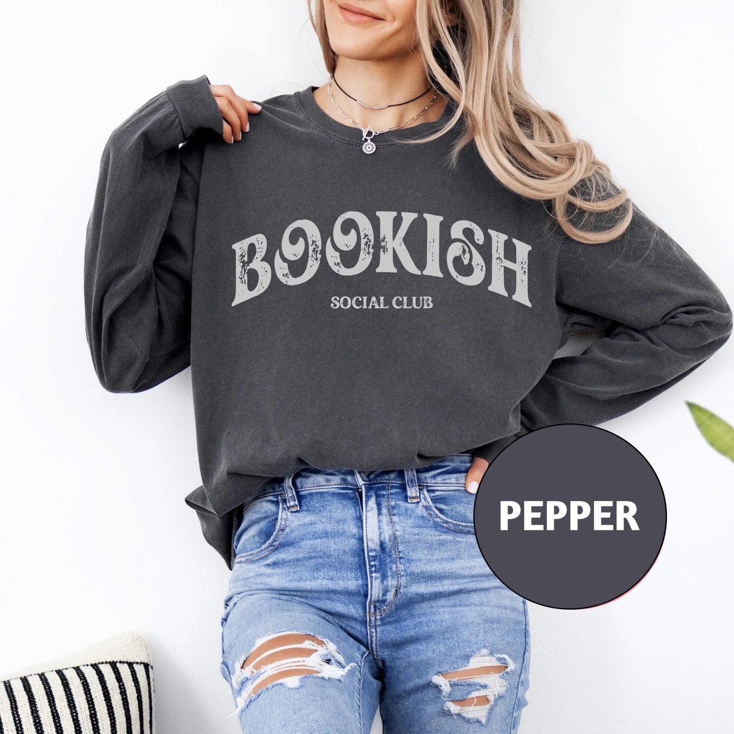 a woman wearing a bookish sweatshirt and ripped jeans