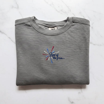 A gray sweatshirt with a blue and red embroidered design on the front, which says "Land of the free".