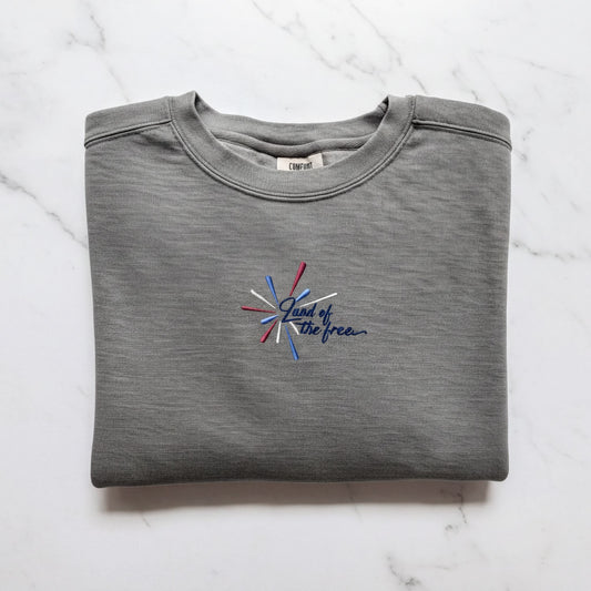 A gray sweatshirt with a blue and red embroidered design on the front, which says "Land of the free".