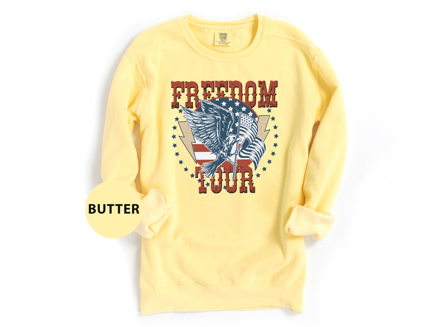 A yellow sweatshirt with a graphic design featuring an eagle and the word "FREEDOM TOUR" printed on it.