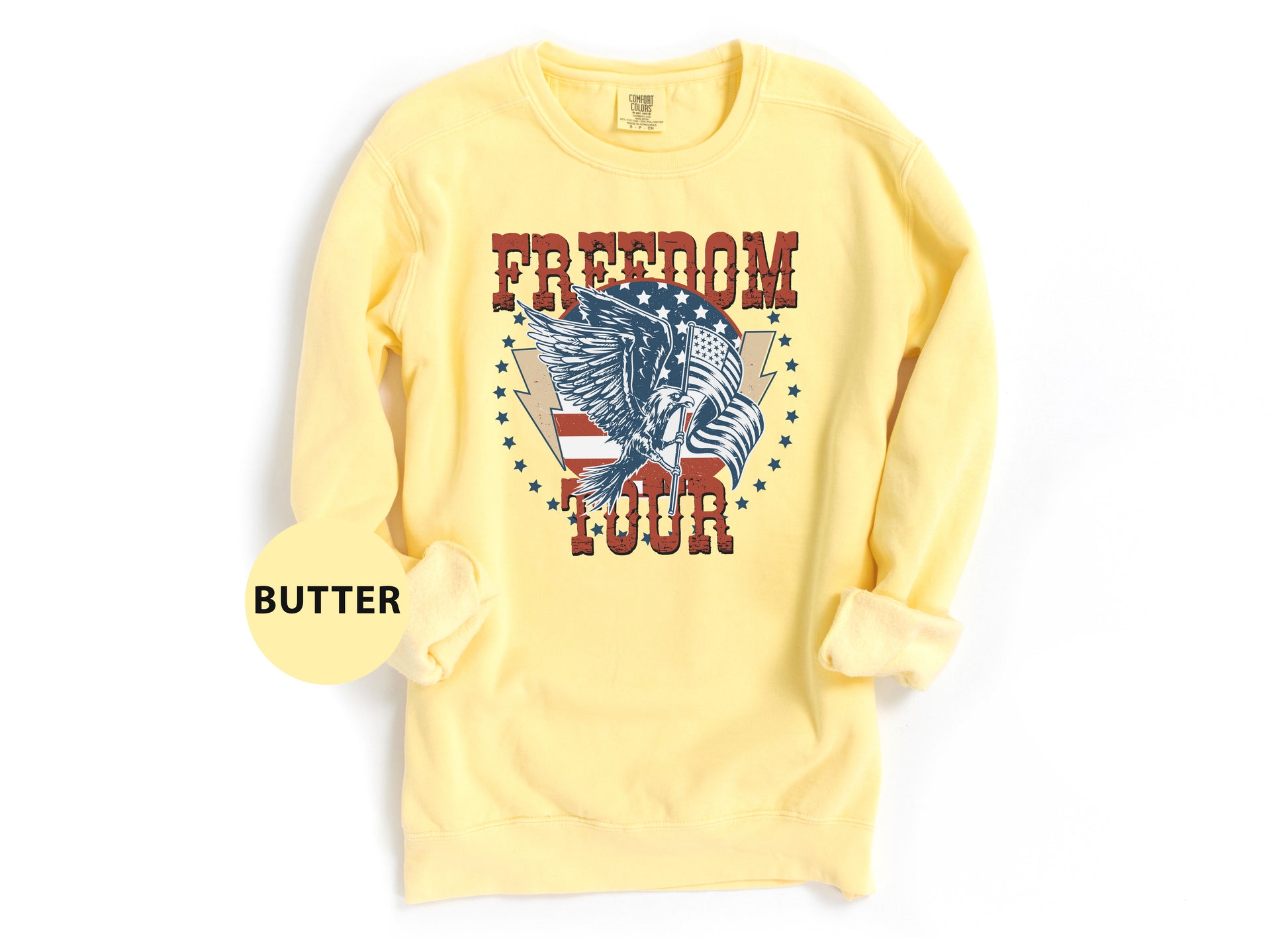 A yellow sweatshirt with a graphic design featuring an eagle and the word "FREEDOM TOUR" printed on it.