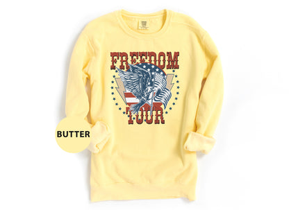 A yellow sweatshirt with a graphic design featuring an eagle and the word "FREEDOM TOUR" printed on it.
