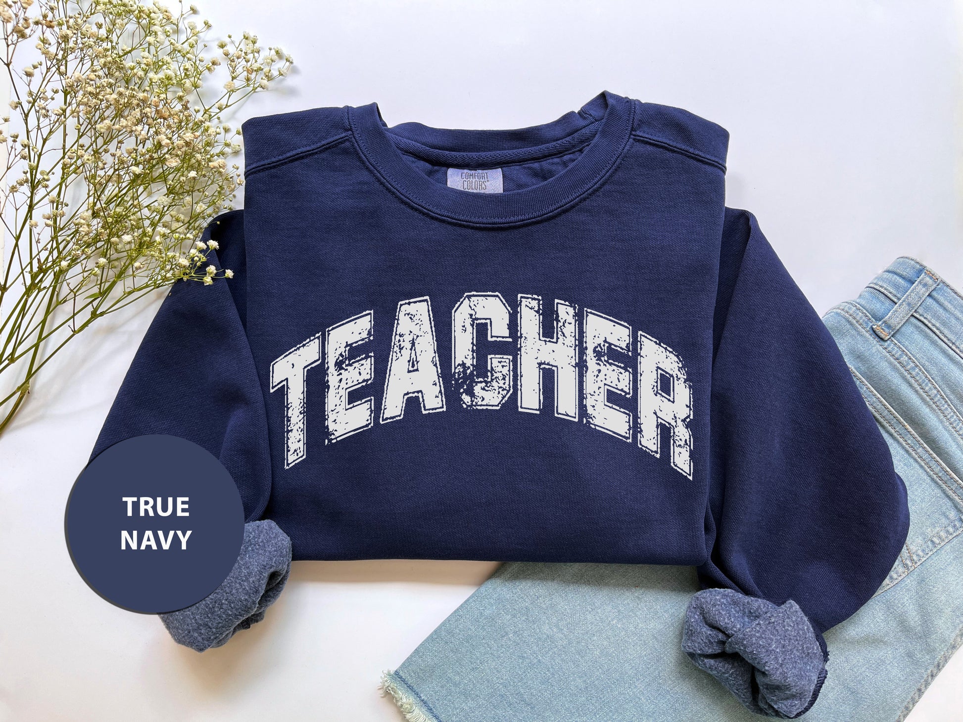 a t - shirt with the word teacher on it next to a pair of jeans