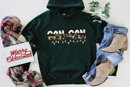 A green hoodie with a Christmas-themed design, a pair of jeans, a pair of boots, and some holiday-themed accessories such as a scarf and a card with a "Merry Christmas" message.