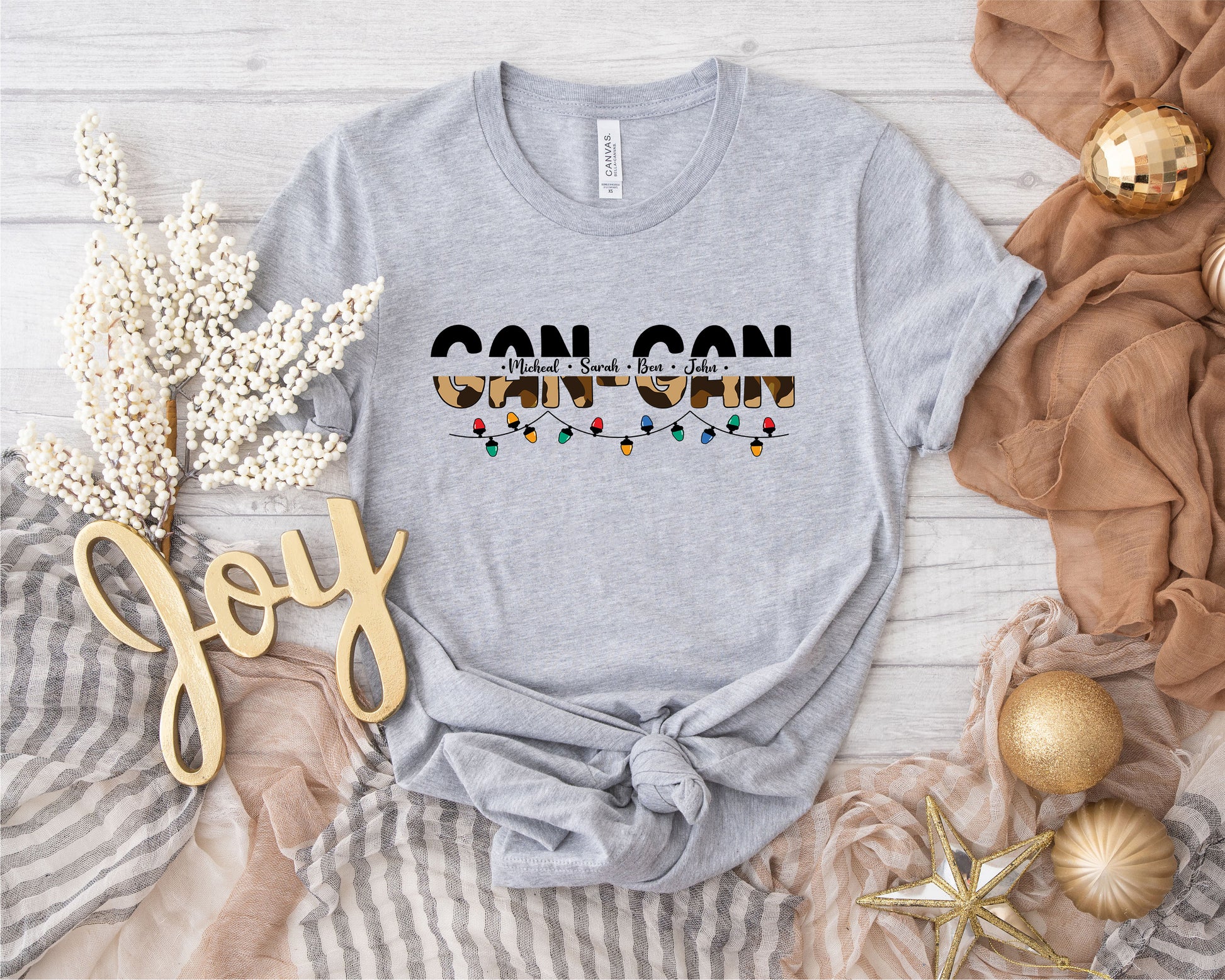 a gray t-shirt with a graphic design, a gold star, and some decorative elements such as a gold star, a gold ball, and a gold ribbon.