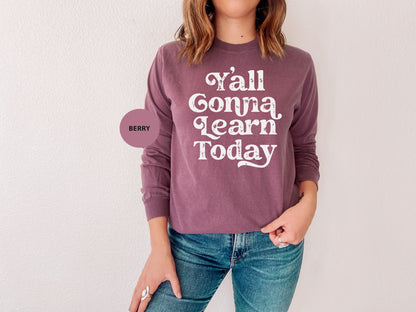 a woman wearing a sweater that says y'all comma learn today