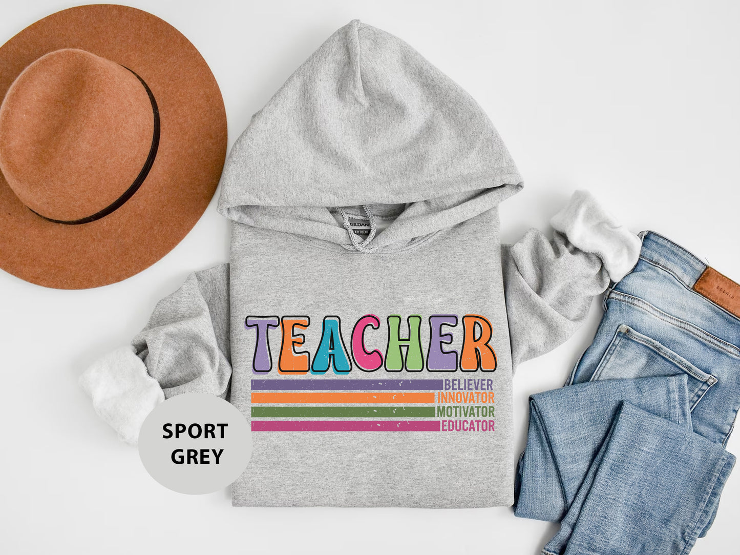 a gray hoodie with the words teacher on it next to a pair of jeans