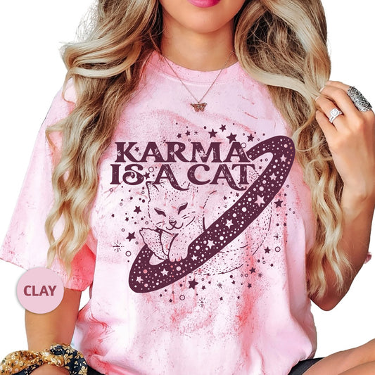 a woman wearing a pink t - shirt that says karma is a cat