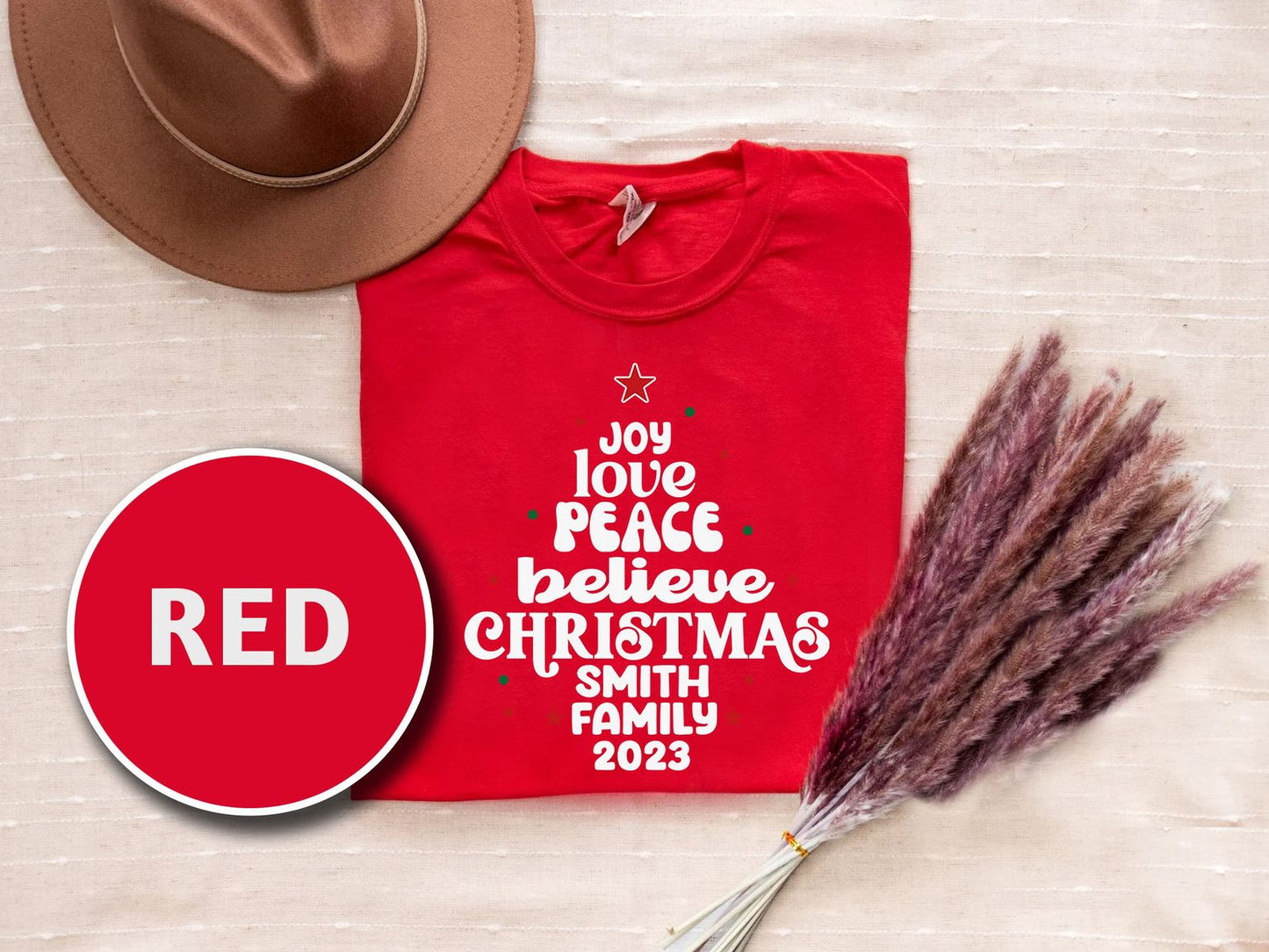 a red t-shirt with white text, a brown hat, and some pom poms, all arranged on a beige background.