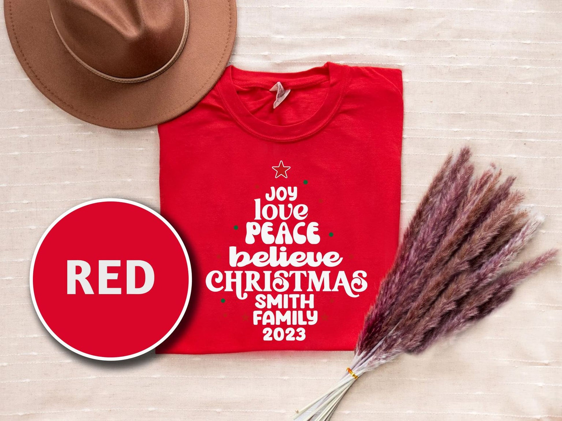 a red t-shirt with white text, a brown hat, and some pom poms, all arranged on a beige background.