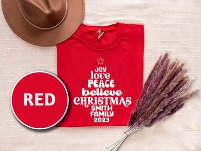 a red t-shirt with white text, a brown hat, and some pom poms, all arranged on a beige background.