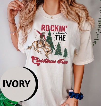 A woman wearing a white t-shirt with a graphic design of a cowboy riding a horse and a Christmas tree.