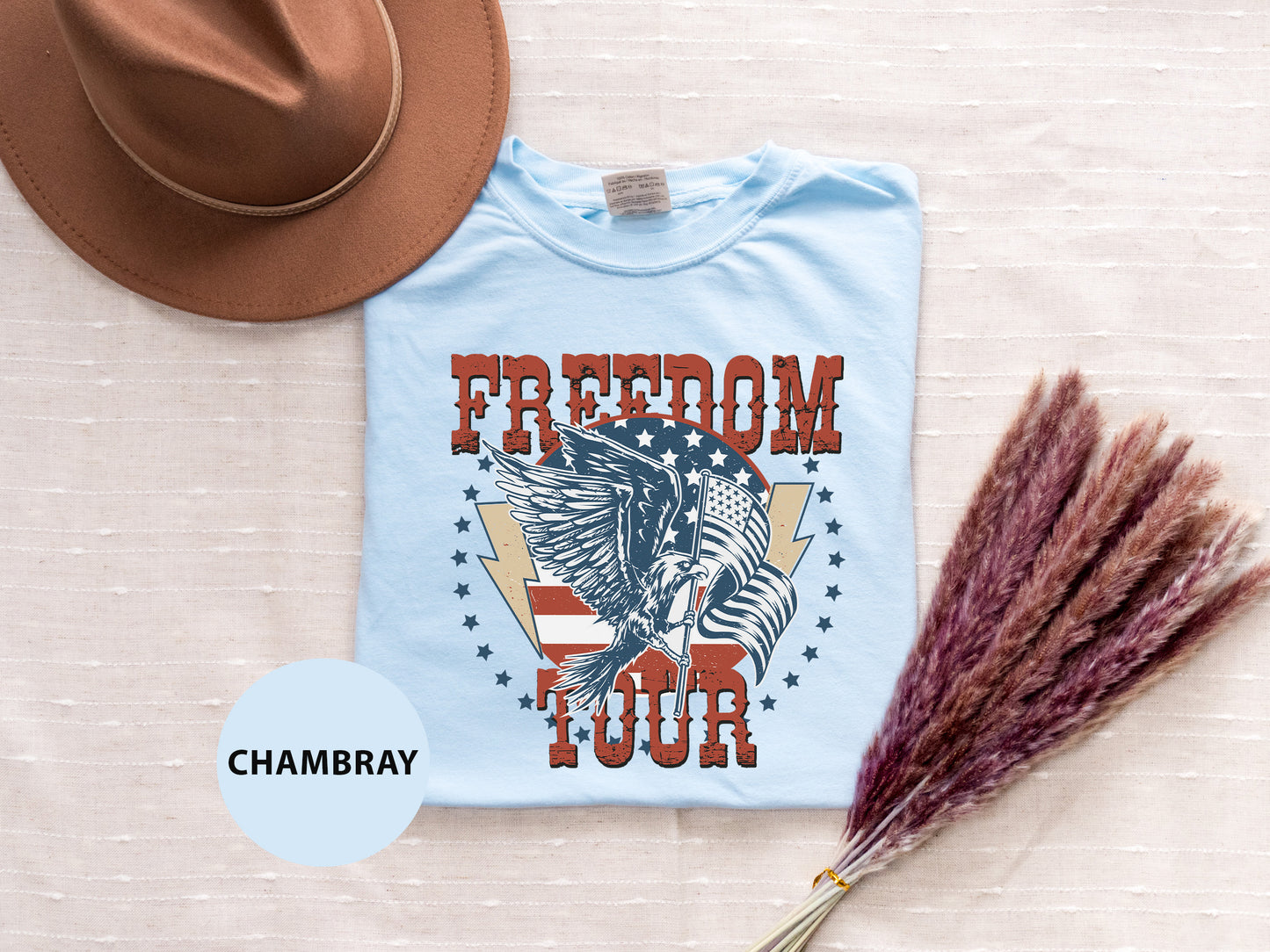 a blue t-shirt with a graphic design, a brown hat, and a bunch of purple flowers, all arranged on a white background.
