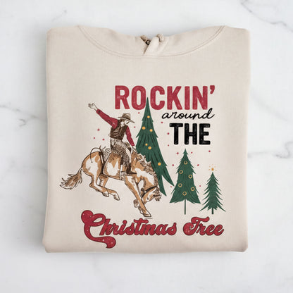 The image is a t-shirt design featuring a cowboy riding a bucking bronco, with Christmas trees and the phrase "Rockin' around the Christmas Tree" written on it.