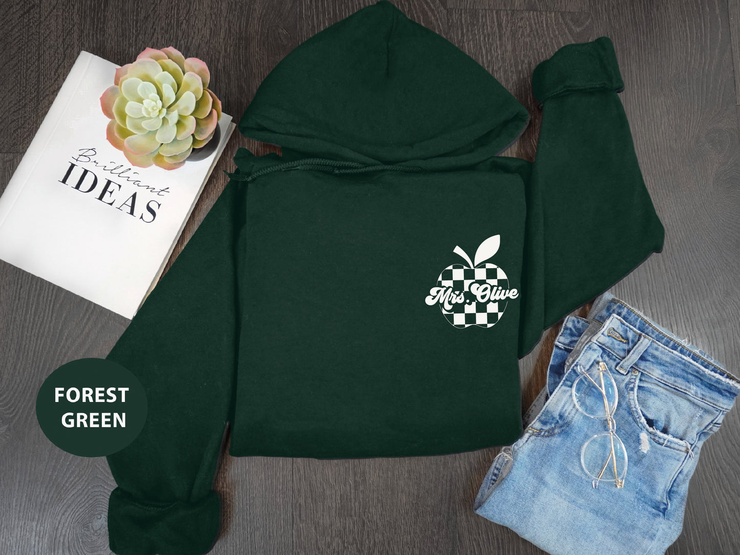 a green hoodie with an apple on it next to a book