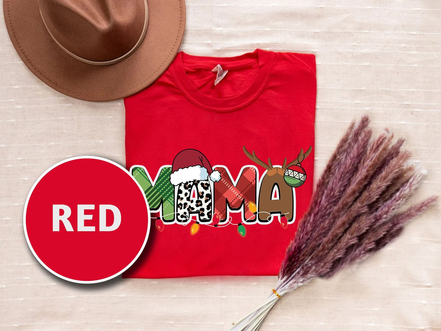 a red t-shirt with a Christmas-themed design, a brown hat, and some pom poms on a beige background.