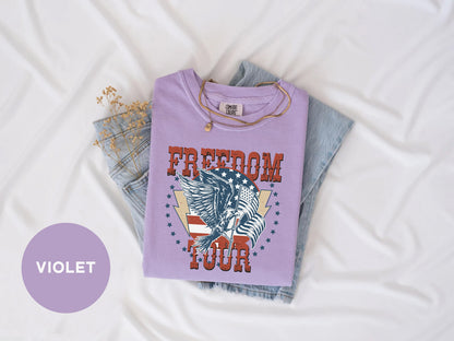 a purple t-shirt with a graphic design, a pair of jeans, and some dried flowers on a white background.