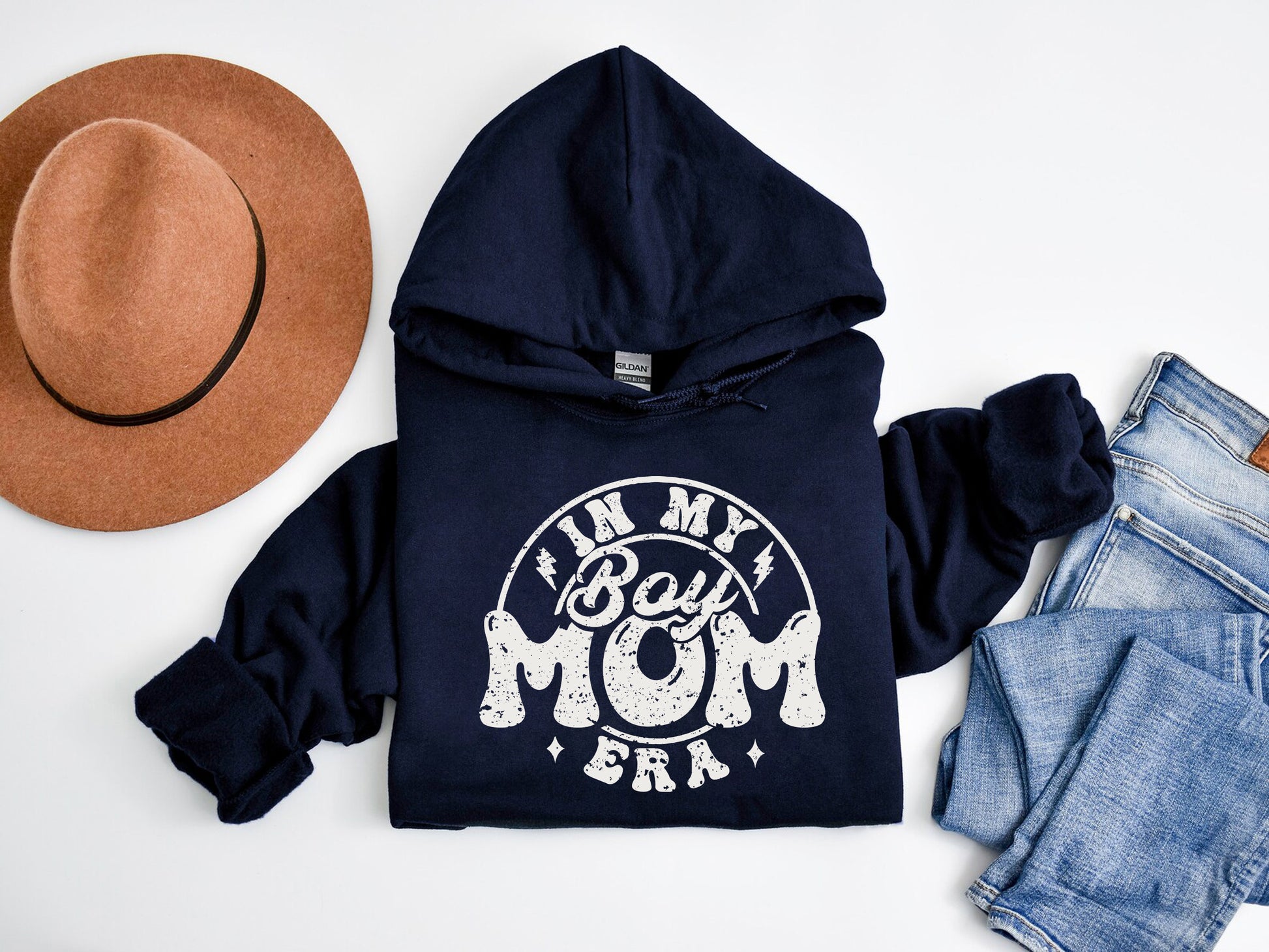 a hoodie, jeans, hat, and a pair of shoes on a white