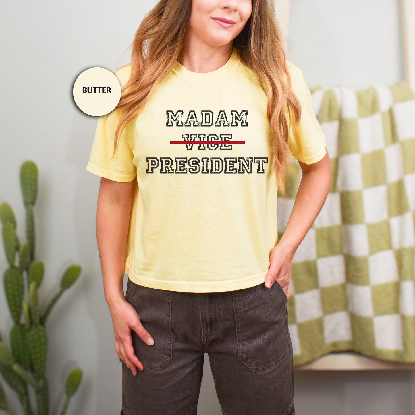 a woman in a yellow shirt is standing in front of a cactus