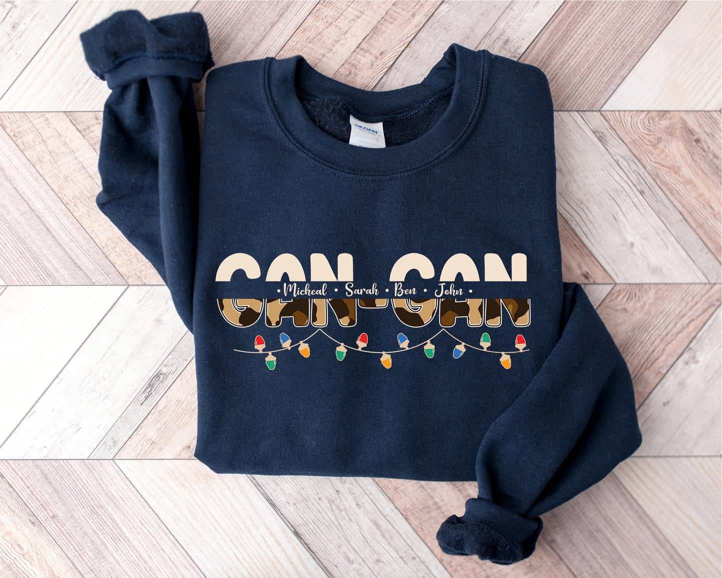 A navy blue sweatshirt with the text "CAN CAN" printed on it, along with the names "Michael", "Sara", and "John" arranged in a decorative pattern.