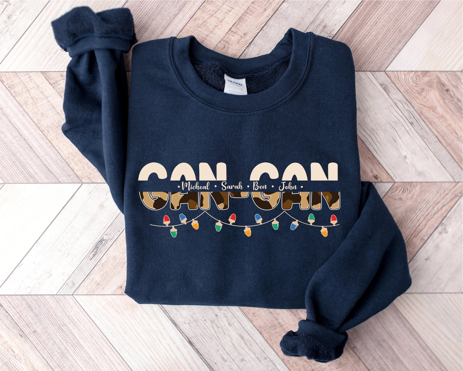 A navy blue sweatshirt with the text "CAN CAN" printed on it, along with the names "Michael", "Sara", and "John" arranged in a decorative pattern.