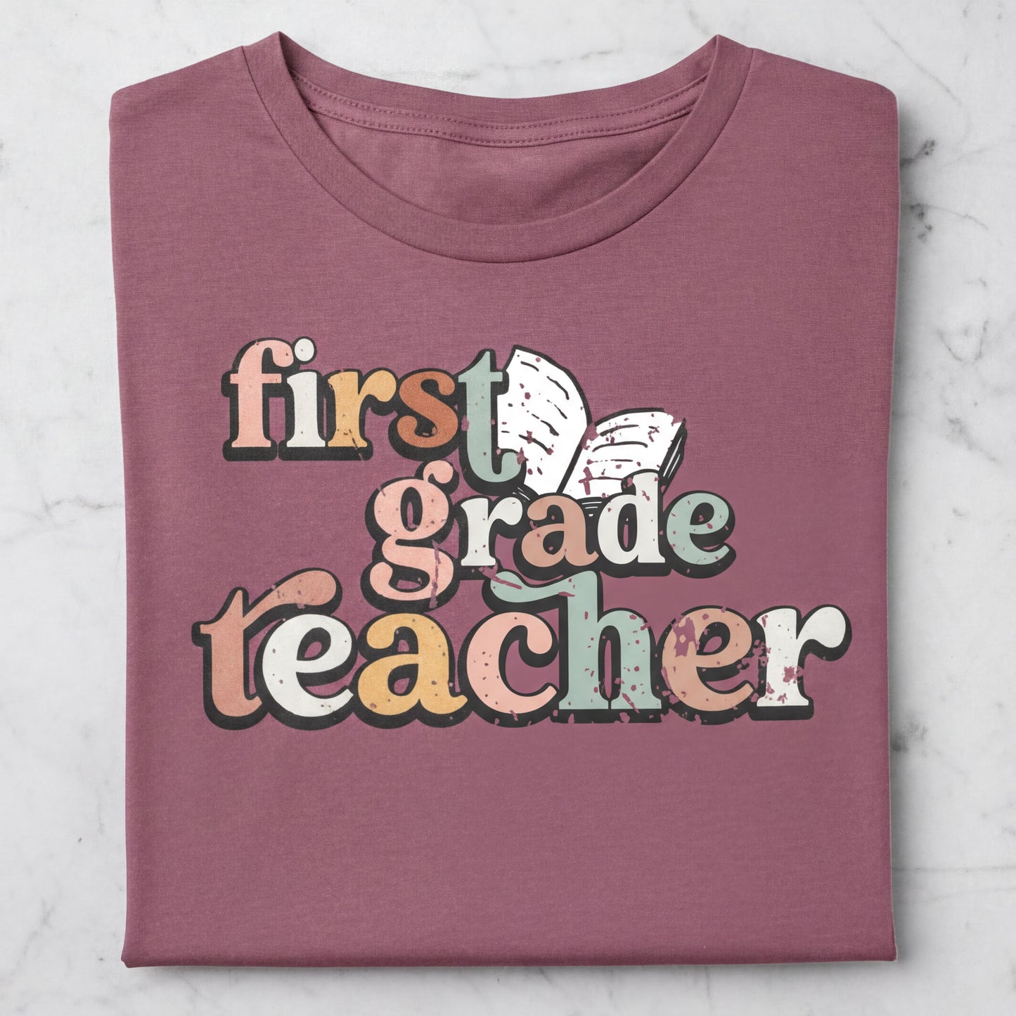 A pink t-shirt with the text "first grade teacher" printed on it.