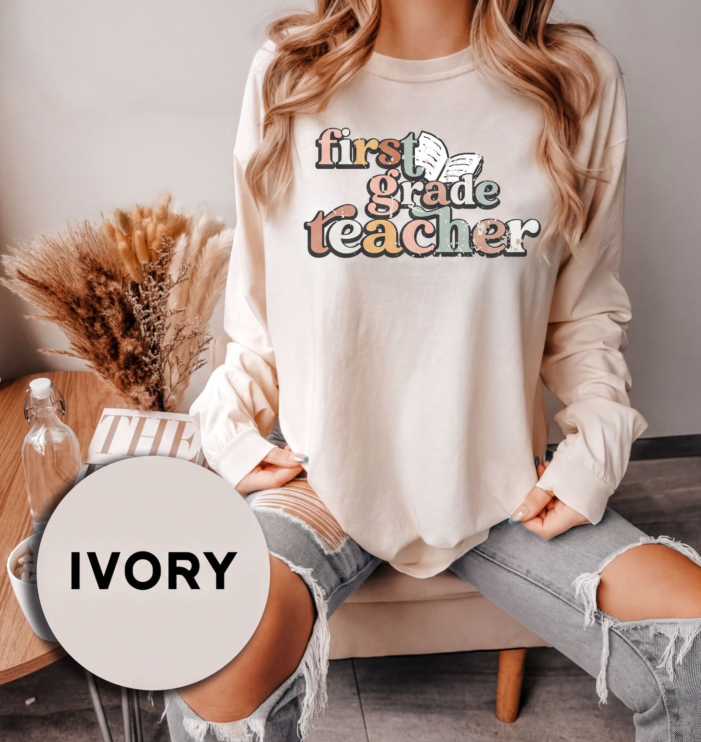 A woman wearing a white long-sleeved shirt with text and graphics printed on it, sitting on a chair.
