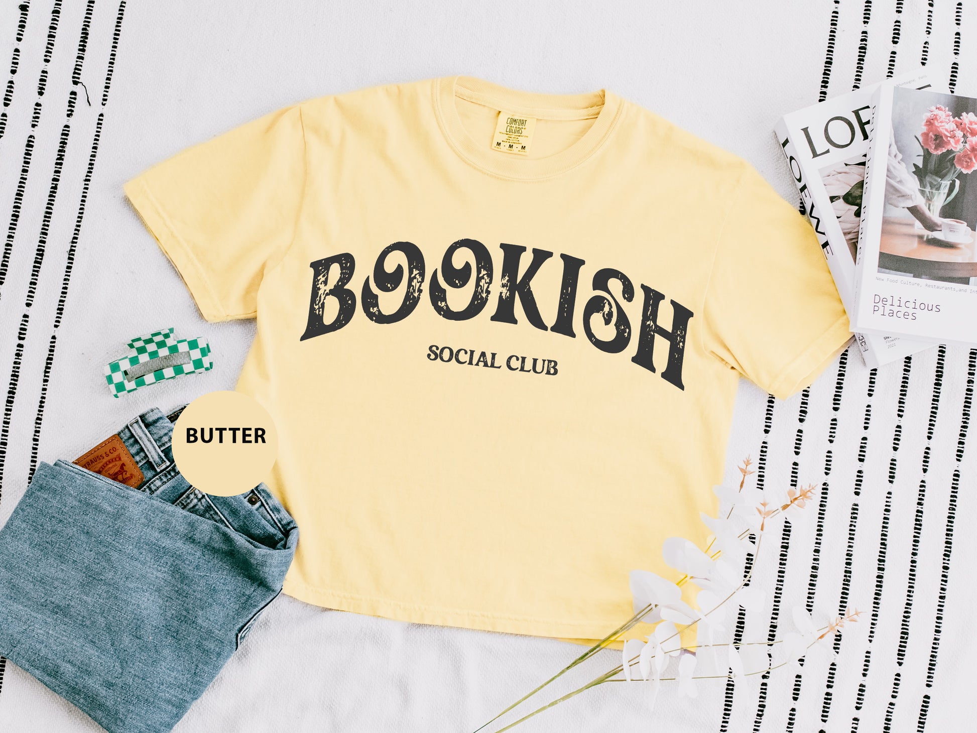 a t - shirt that says bookish social club next to a pair of jeans