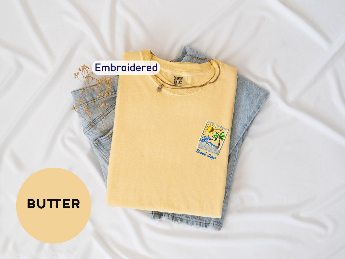 a yellow t-shirt with a small patch on the front, along with a pair of blue jeans, laid out on a white surface.
