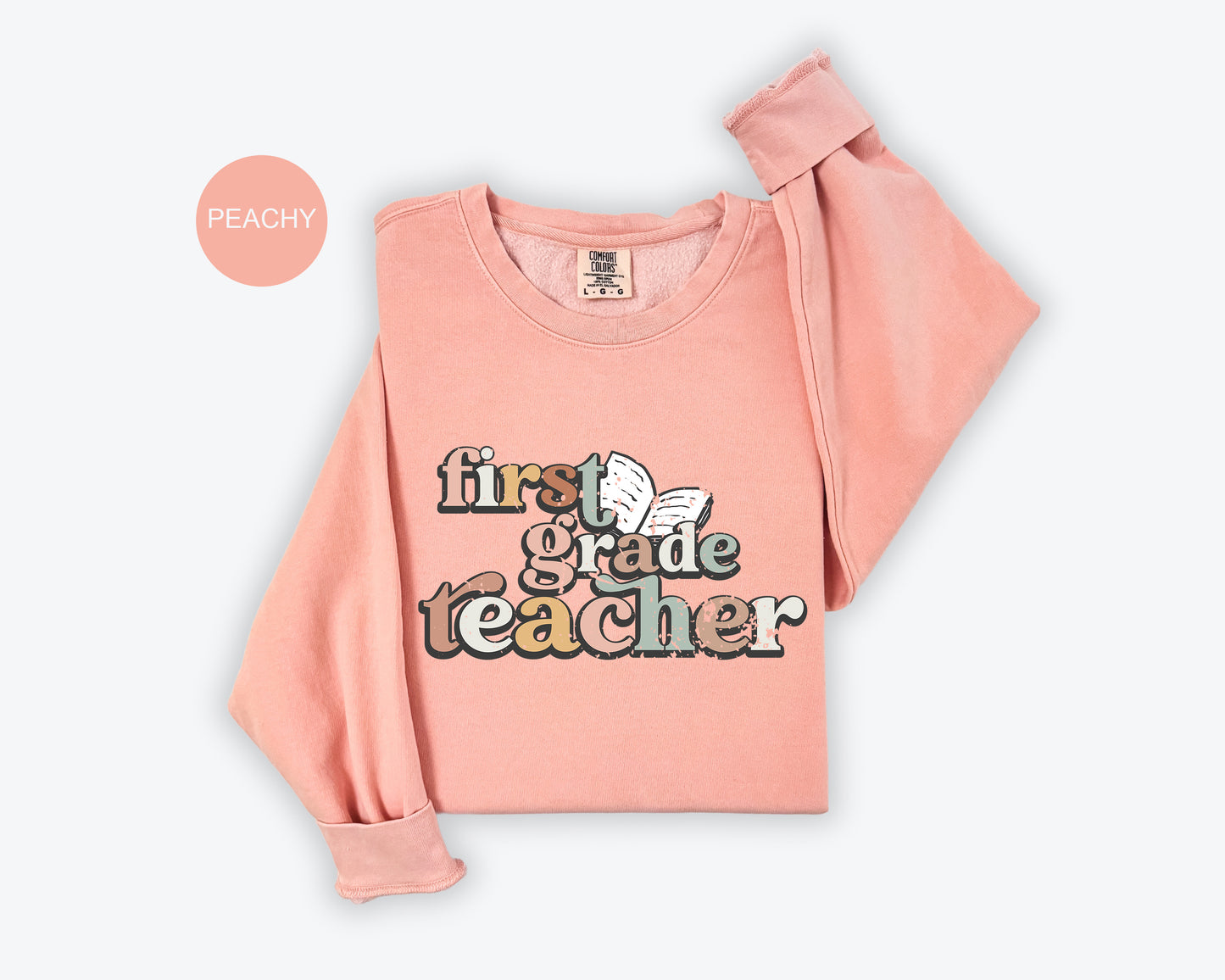 A pink sweatshirt with the text "first grade teacher" printed on it.