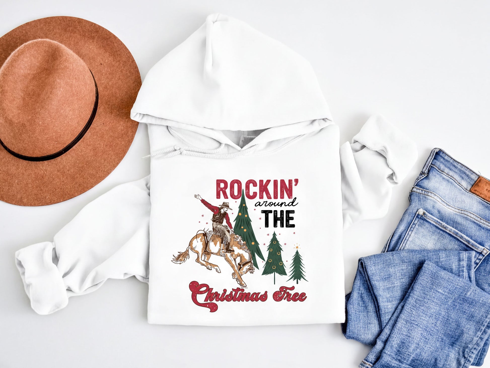 A white hoodie with a graphic design, a brown hat, and a pair of blue jeans are arranged on a white background.